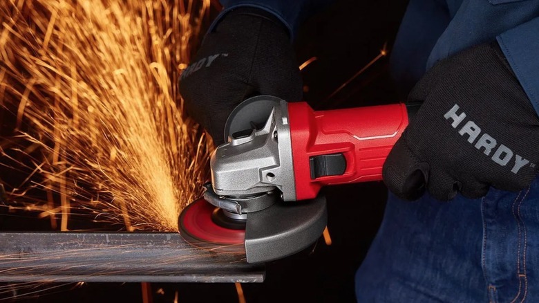 A person using a Bauer angle grinder on a metal workpiece, creating sparks.