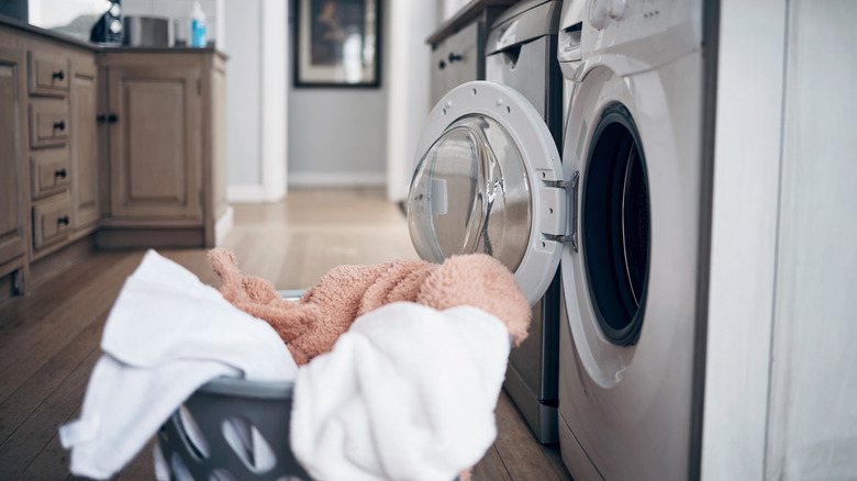 Laundry basket with clothes next to an open dryer door.