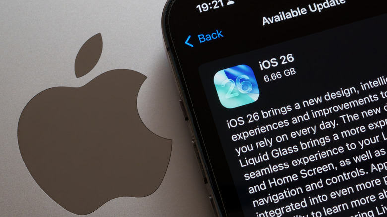 An iPhone displaying the iOS 26 update screen sitting on a laptop.