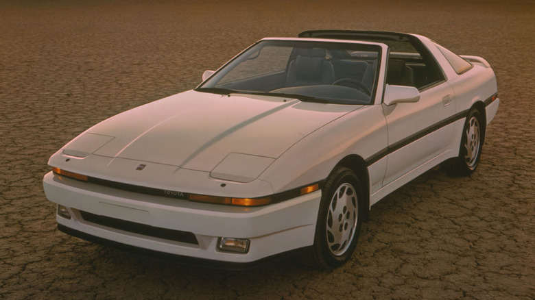 A silver 1989 Toyota Supra Targa with pop-up headlights parked at sunset