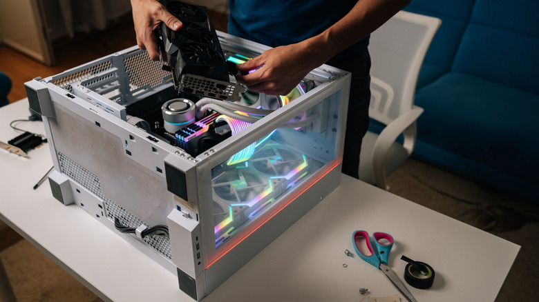 A person installing a high-end graphics card into a PC, representing the comparison between desktop and laptop GPU power.