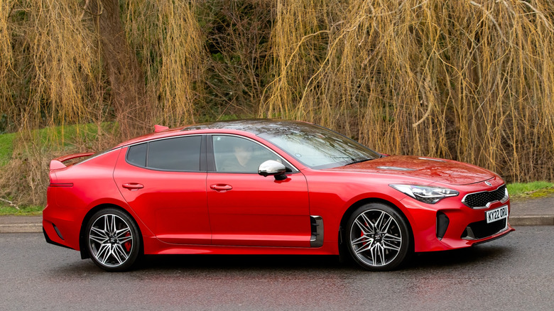 A metallic Kia Stinger GT driving along a winding country road.