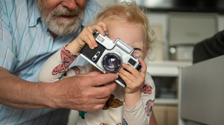A close-up of a child looking intently through a camera viewfinder.