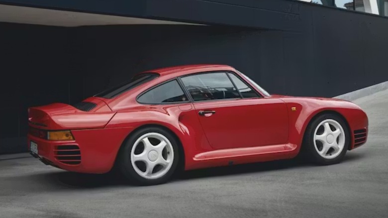 Studio shot of a red Porsche 959 against a dark background.