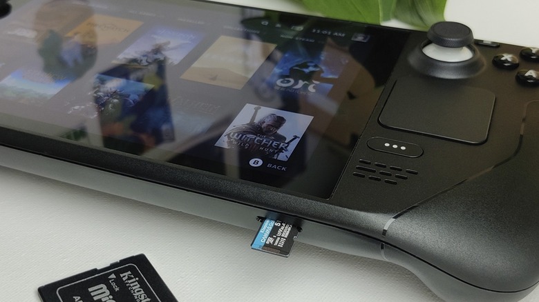 A close-up of a Steam Deck with a microSD card being inserted into the slot.