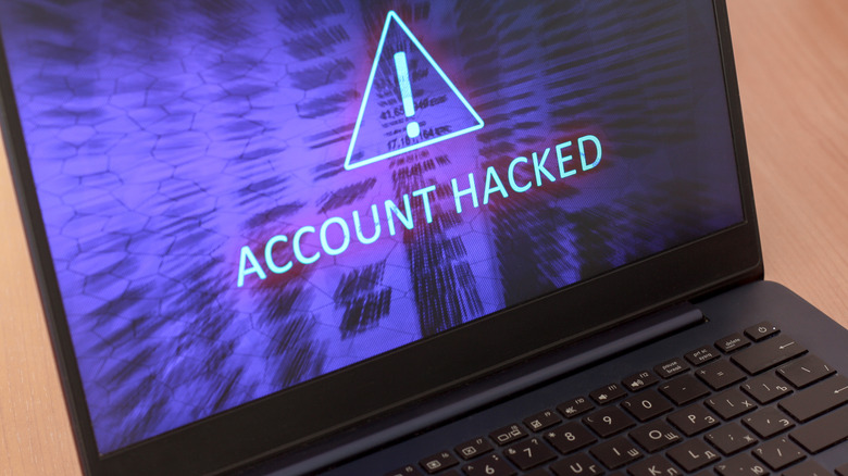 A laptop screen displaying a large 'Account Hacked' warning and a red alert icon.