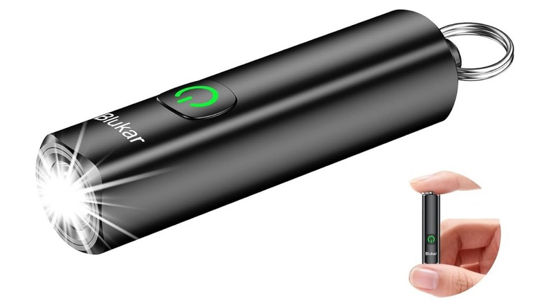 A small black Blukar LED flashlight held between a thumb and index finger to show its miniature size.