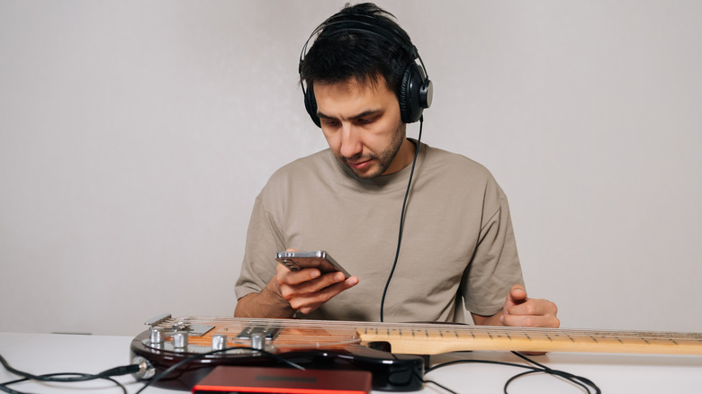 A person intently looking at their smartphone while wearing over-ear professional headphones.