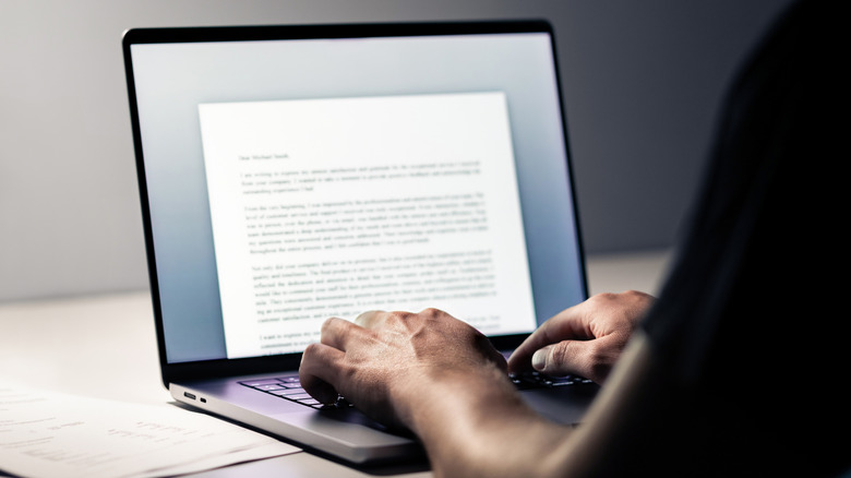 Close-up of hands typing on a laptop keyboard in a minimalist workspace.