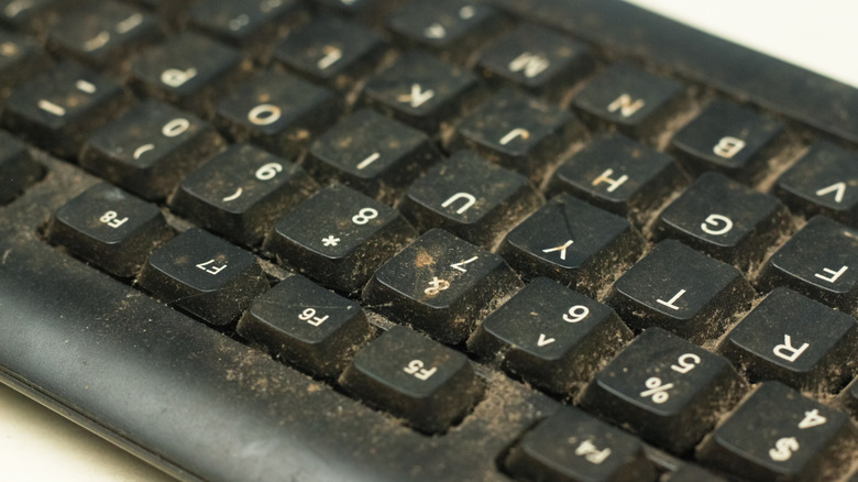Macro view of extreme dust and debris buildup between mechanical keyboard switches.