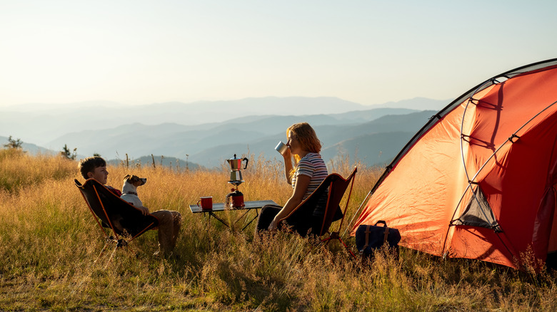Two campers sitting near their tent overlooking a valley