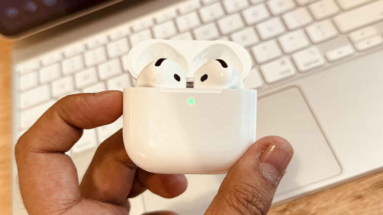 A person holding the AirPods 4 case with the lid open, ready for pairing.