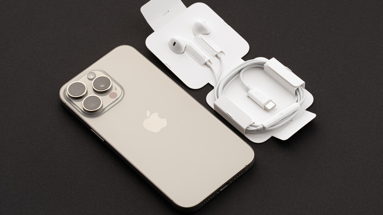USB-C Apple EarPods and their packaging placed next to a modern smartphone on a wooden surface.