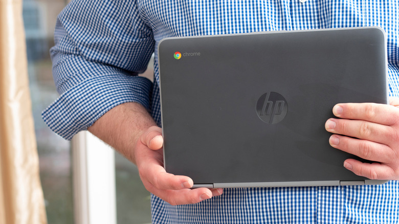 A high-angle view of a person holding an HP Chromebook.