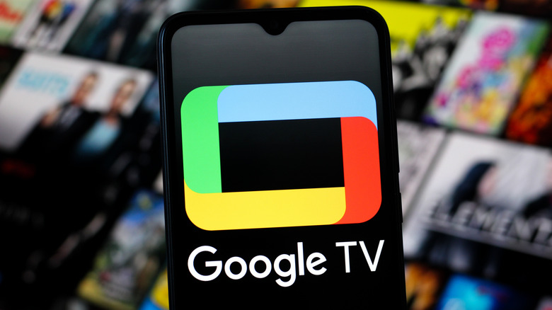 A smartphone displaying the Google TV logo in front of a blurred television screen.