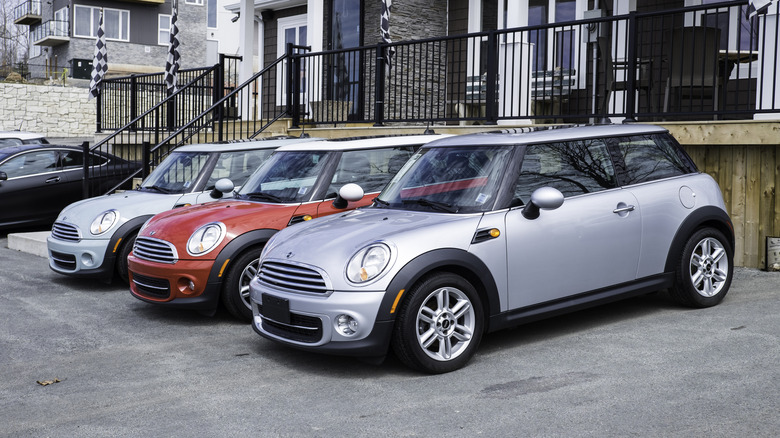 Three Mini Coopers lined up outside a house.