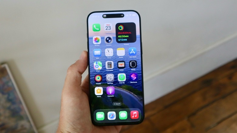 iOS 26 home screen displaying updated Liquid Glass icons with translucent depth effects.